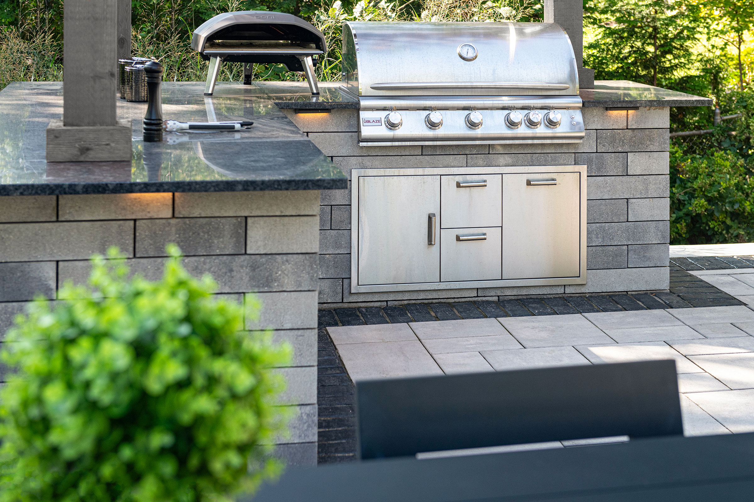 Outdoor kitchen with masonry base, stainless grill and pizza oven