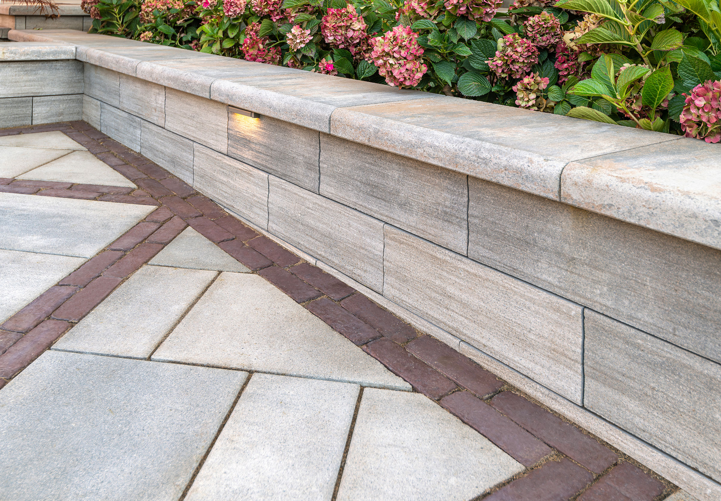 Natural stone seating wall with landscape lighting and hydrangeas